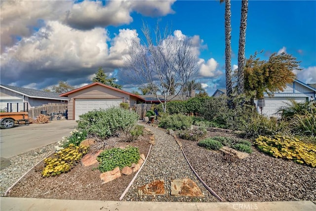 view of front facade with an attached garage, concrete driveway, and fence