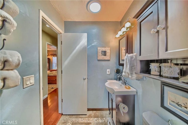 bathroom featuring toilet, vanity, baseboards, and wood finished floors