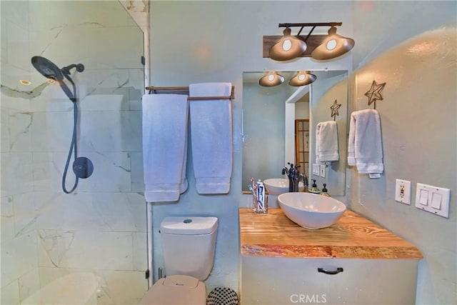 full bathroom featuring toilet, vanity, and a tile shower