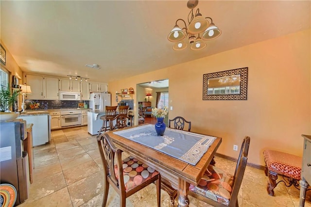 dining space with a chandelier, rail lighting, and baseboards