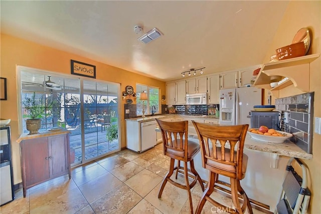 kitchen with visible vents, decorative backsplash, white appliances, white cabinetry, and a sink