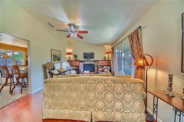 living room featuring a wealth of natural light, visible vents, wood finished floors, and vaulted ceiling