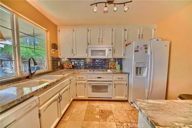 kitchen with a sink, backsplash, white cabinetry, white appliances, and light stone countertops