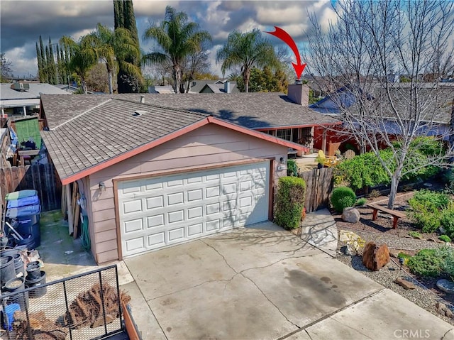 garage featuring concrete driveway and fence