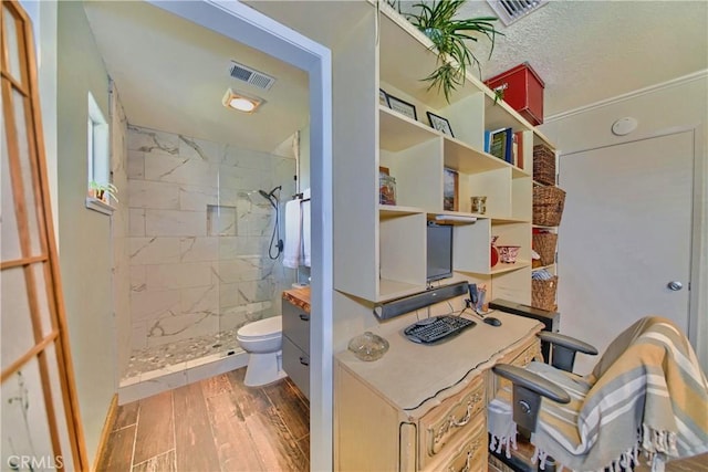 full bath featuring toilet, wood finished floors, visible vents, and tiled shower