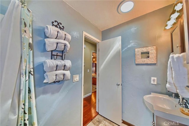 bathroom with a sink, baseboards, and wood finished floors