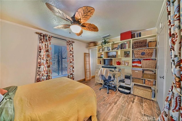 bedroom with visible vents, ceiling fan, ornamental molding, wood finished floors, and a textured ceiling