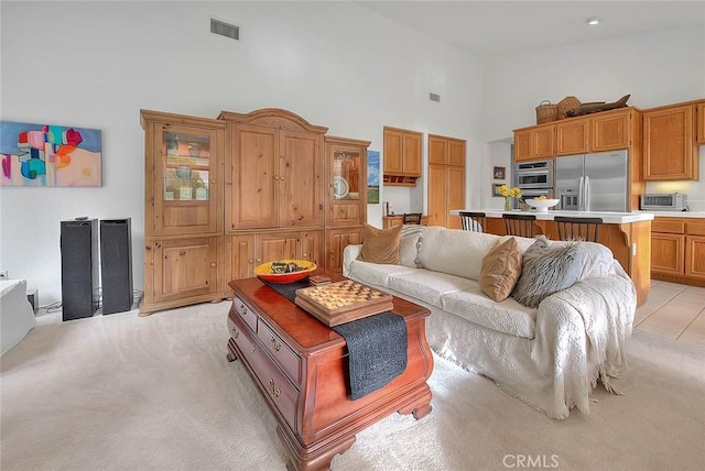 living area with a toaster, light colored carpet, visible vents, and high vaulted ceiling