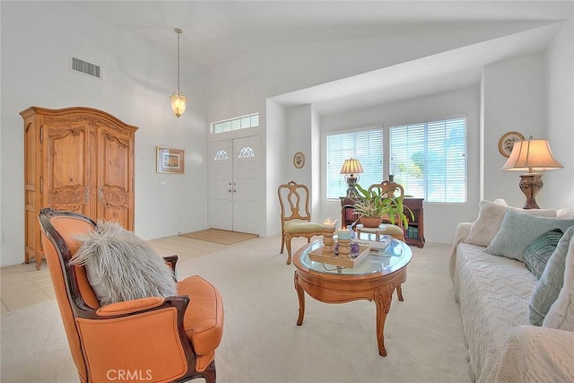 living room featuring visible vents, high vaulted ceiling, and light colored carpet