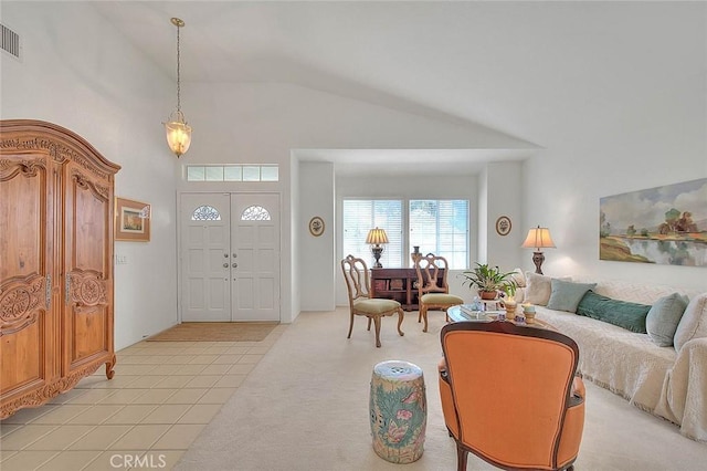 foyer entrance featuring light tile patterned floors, visible vents, light colored carpet, and high vaulted ceiling