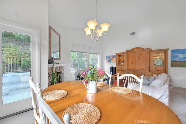 dining space featuring visible vents, a fireplace, an inviting chandelier, and a towering ceiling