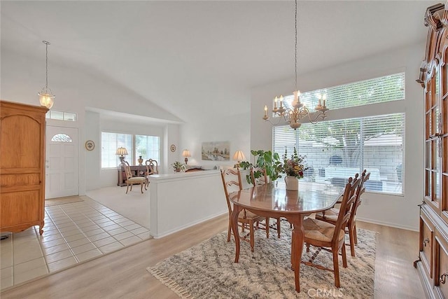 dining area featuring light wood-style floors, a notable chandelier, and high vaulted ceiling