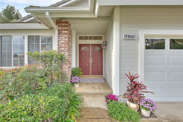 entrance to property featuring a garage, visible vents, and brick siding