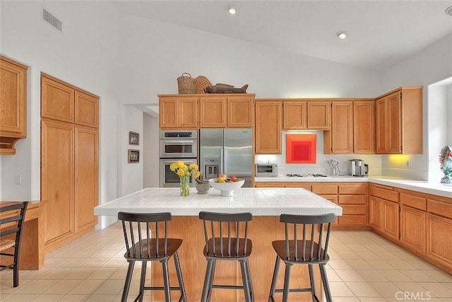 kitchen with tile countertops, light tile patterned floors, visible vents, a toaster, and appliances with stainless steel finishes