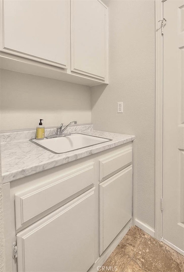 laundry room with baseboards and a sink