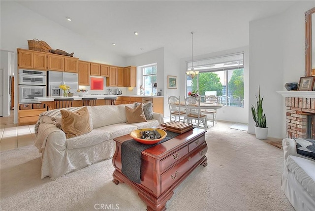 living area featuring high vaulted ceiling, recessed lighting, light colored carpet, a brick fireplace, and a chandelier