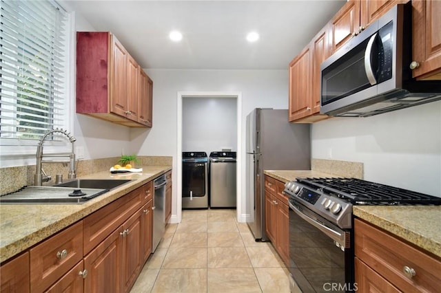 kitchen featuring light tile patterned floors, recessed lighting, a sink, stainless steel appliances, and washer and dryer