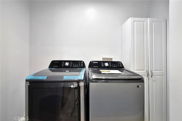 clothes washing area with washer and dryer and cabinet space