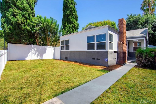 view of front facade with stucco siding, fence, a front yard, crawl space, and a chimney