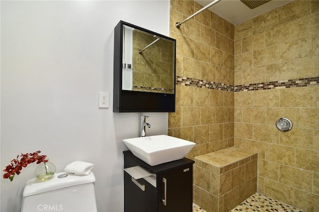full bath featuring tiled shower, toilet, and vanity