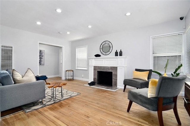 living area with a tiled fireplace, light wood-style flooring, recessed lighting, and baseboards