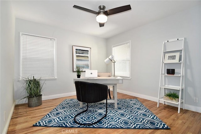 home office with baseboards, a ceiling fan, and light wood-style floors