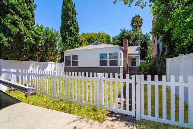 view of front of home with a front yard, a chimney, a fenced front yard, and stucco siding