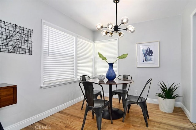 dining room with a chandelier, baseboards, and light wood-style flooring