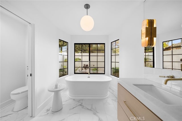 bathroom featuring a wealth of natural light, marble finish floor, and a freestanding tub