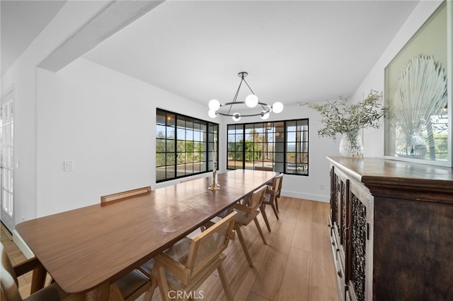 dining area featuring a notable chandelier, baseboards, and light wood finished floors