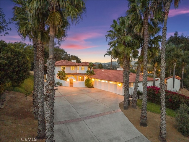 mediterranean / spanish-style home with stucco siding, driveway, a tile roof, and a garage