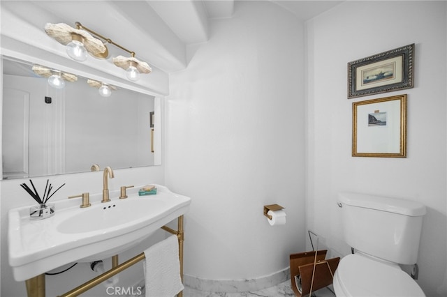 half bath with toilet, baseboards, and a sink