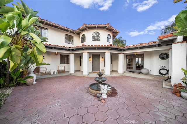 rear view of house featuring a patio area, french doors, a tile roof, and stucco siding