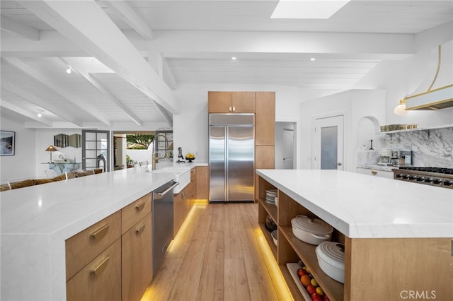 kitchen with open shelves, a peninsula, decorative backsplash, appliances with stainless steel finishes, and modern cabinets