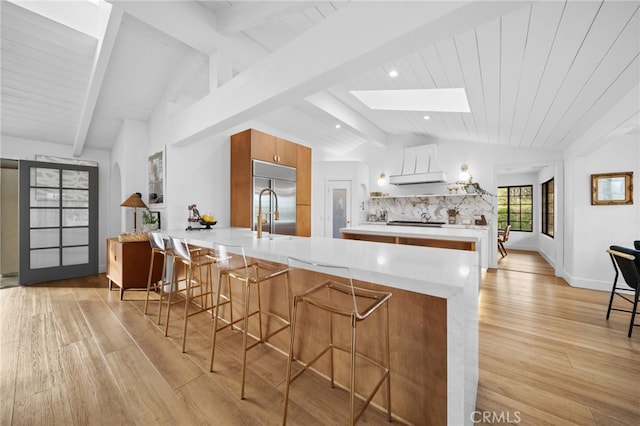 kitchen with brown cabinetry, a peninsula, light countertops, and stainless steel built in fridge