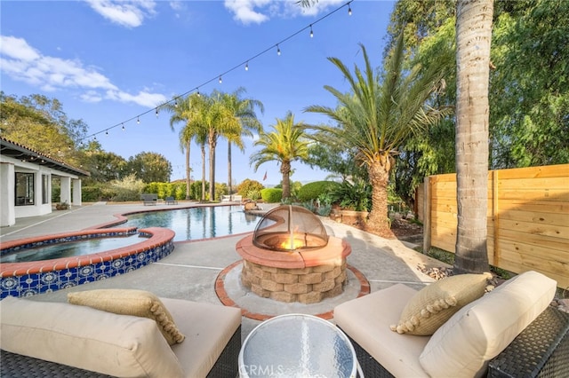 view of pool featuring a patio area, a pool with connected hot tub, an outdoor living space with a fire pit, and fence