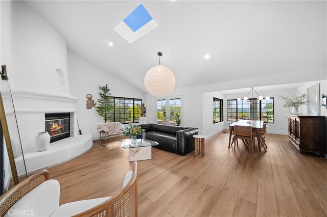 living area featuring recessed lighting, light wood-type flooring, a large fireplace, and a skylight