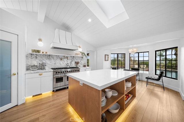 kitchen with double oven range, open shelves, custom range hood, white cabinets, and lofted ceiling with skylight