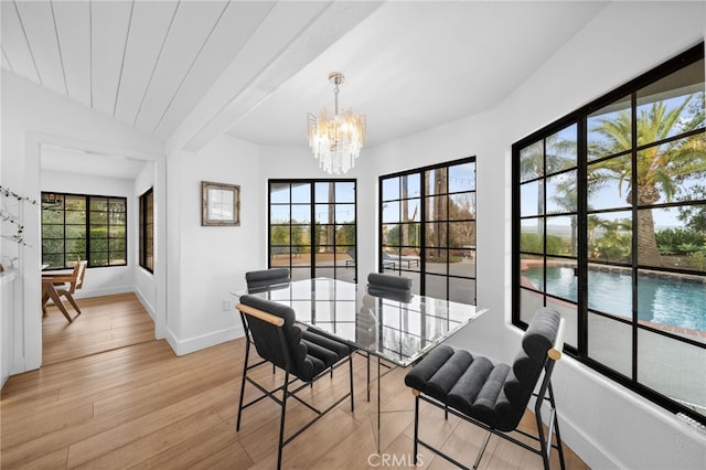 dining space featuring a notable chandelier, baseboards, lofted ceiling, and light wood-style floors