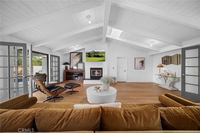 living room featuring lofted ceiling with skylight, wood finished floors, a glass covered fireplace, french doors, and baseboards