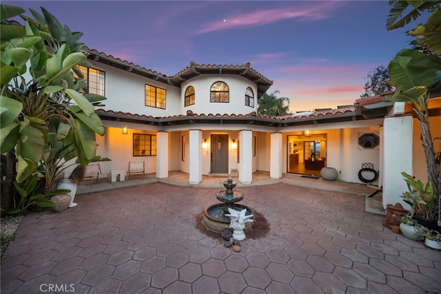 back of house with stucco siding, a patio, and a tile roof