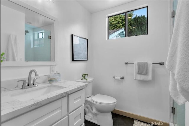 bathroom featuring toilet, a stall shower, tile patterned flooring, baseboards, and vanity