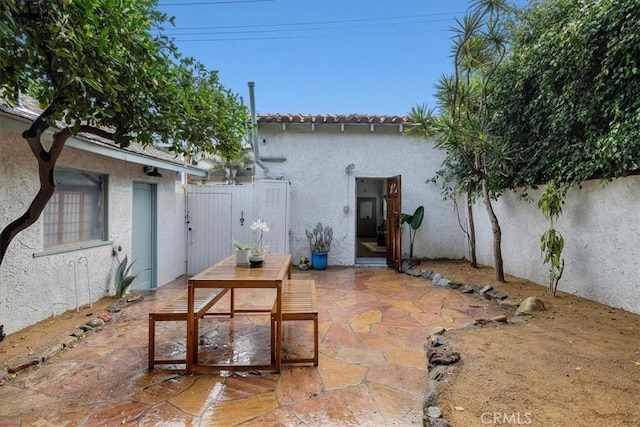 view of patio with a gate, outdoor dining area, and fence