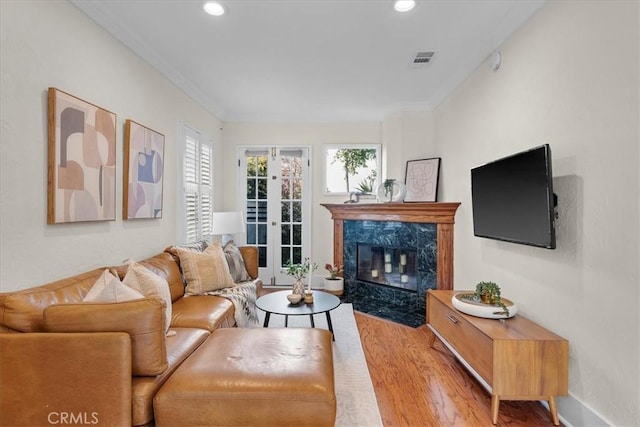 living room with visible vents, wood finished floors, recessed lighting, a fireplace, and crown molding