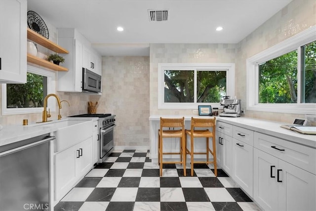 kitchen featuring open shelves, dark floors, visible vents, and appliances with stainless steel finishes