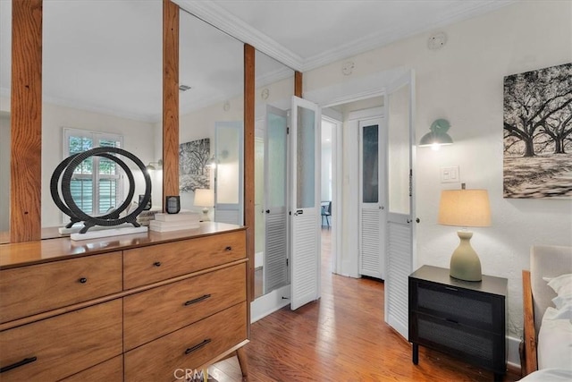 bedroom with wood finished floors and ornamental molding