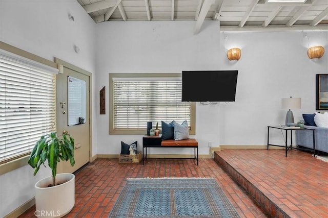 sitting room featuring beamed ceiling, wooden ceiling, baseboards, and brick floor