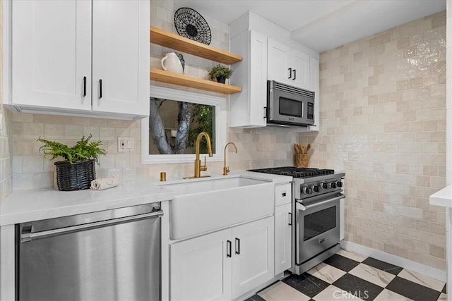 kitchen featuring open shelves, light countertops, tile patterned floors, stainless steel appliances, and a sink