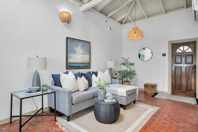 living room featuring beamed ceiling, a high ceiling, wooden ceiling, brick floor, and baseboards