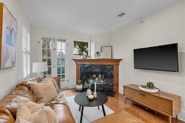 living area featuring wood finished floors, visible vents, french doors, and ornamental molding